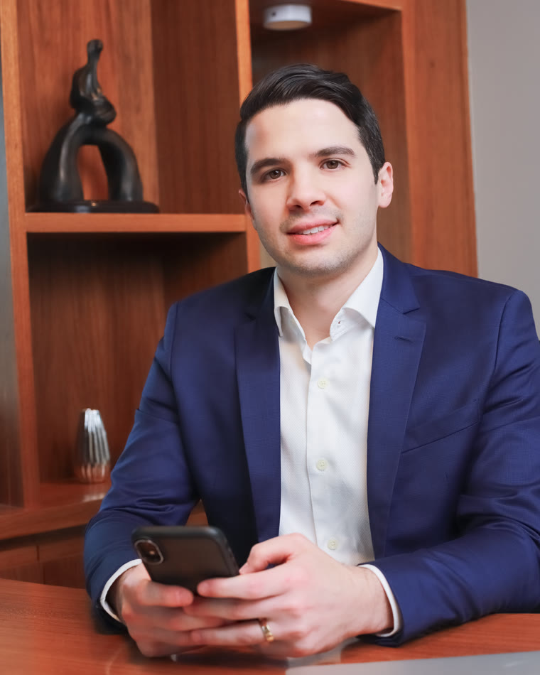 Dr. Danilo Mardegam Razente segurando o celular no consultório, pronto para atender pelo WhatsApp