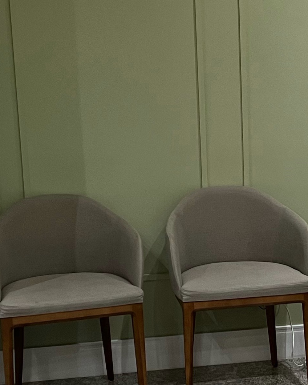 Sala de espera: poltronas com base em madeira diante de boiserie verde-sálvia