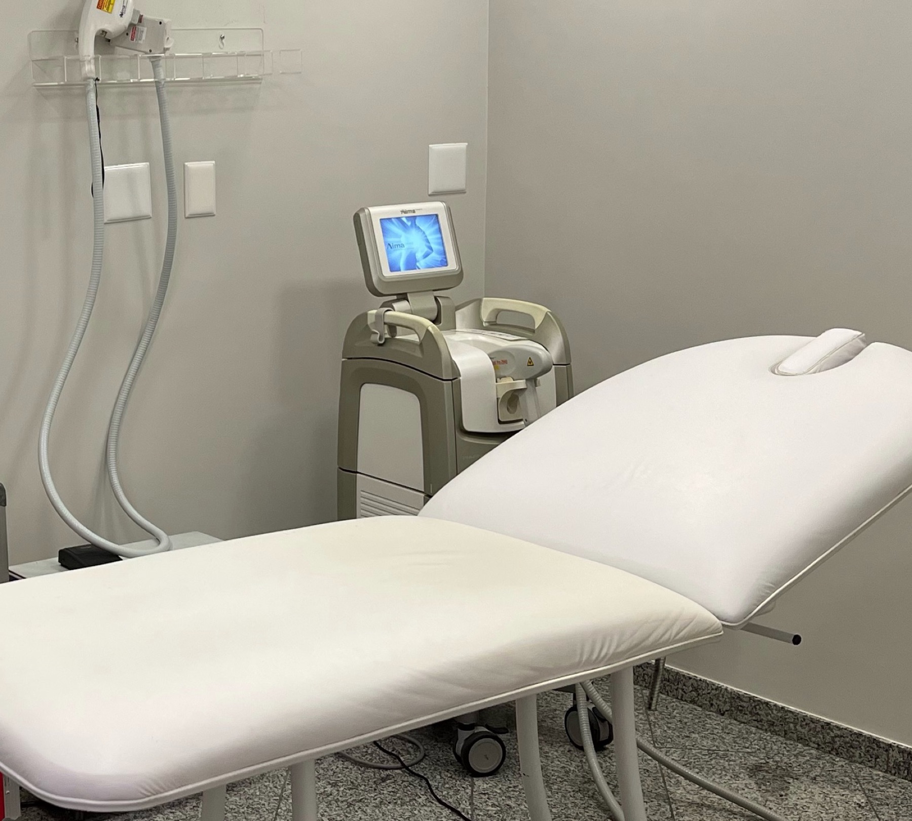 Sala de procedimentos: maca e equipamento de laser e ultrassom microfocado