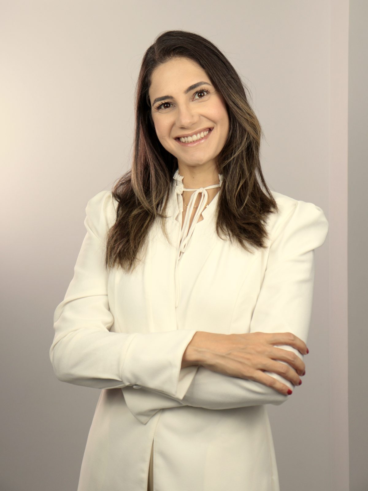 Dra. Stella Meireles, dermatologista, de braços cruzados no consultório